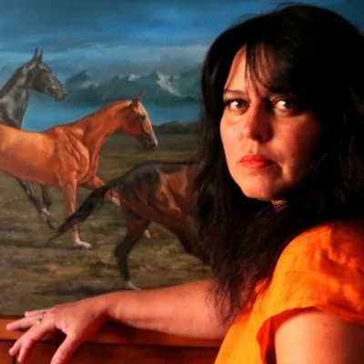 artist standing in a bright painting studio beside canvases